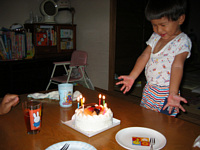 バースデーケーキに火がともったよ!この満面の笑み.火をつけてる側からどんどん吹き消し始めようとしていたよ.